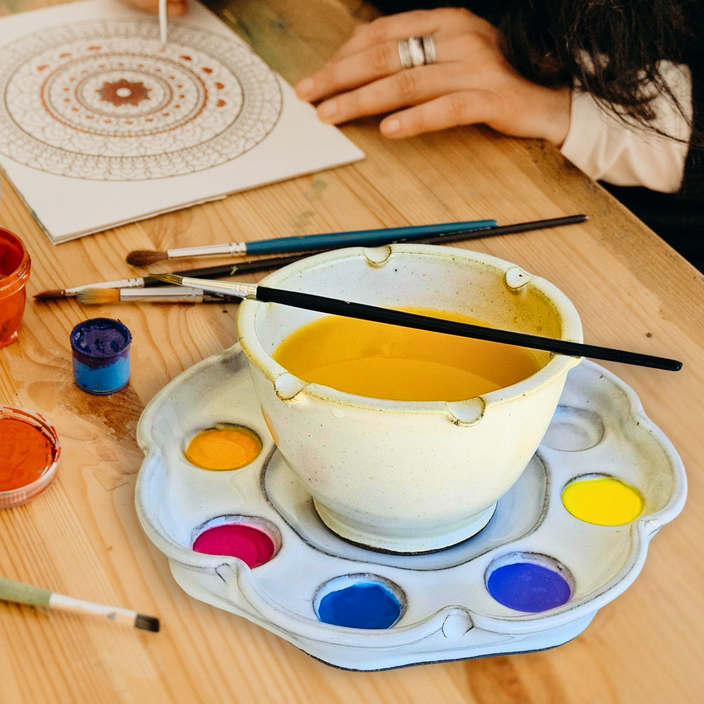 Handmade ceramic paint palette and rinse bowl set with a flower-inspired design. Features eight paint wells, a central mixing area, and built-in brush rests. Perfect for watercolor, acrylic, and mixed media artists.