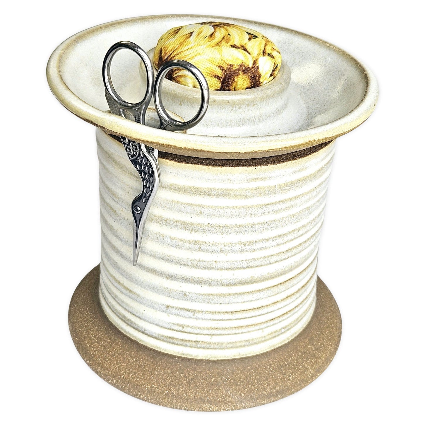 Handcrafted pottery sewing caddy designed to organize creative spaces, featuring compartments for bobbins, scissors, thread spools, and pins. This sturdy and charming piece transforms a cluttered sewing table into an inspiring, tidy workspace. A beautiful and practical gift for sewing moms, grandmothers and aunts who appreciate thoughtful, artisanal tools. The Mud Place, handmade in the USA, white, sunflowers fabric pincushion