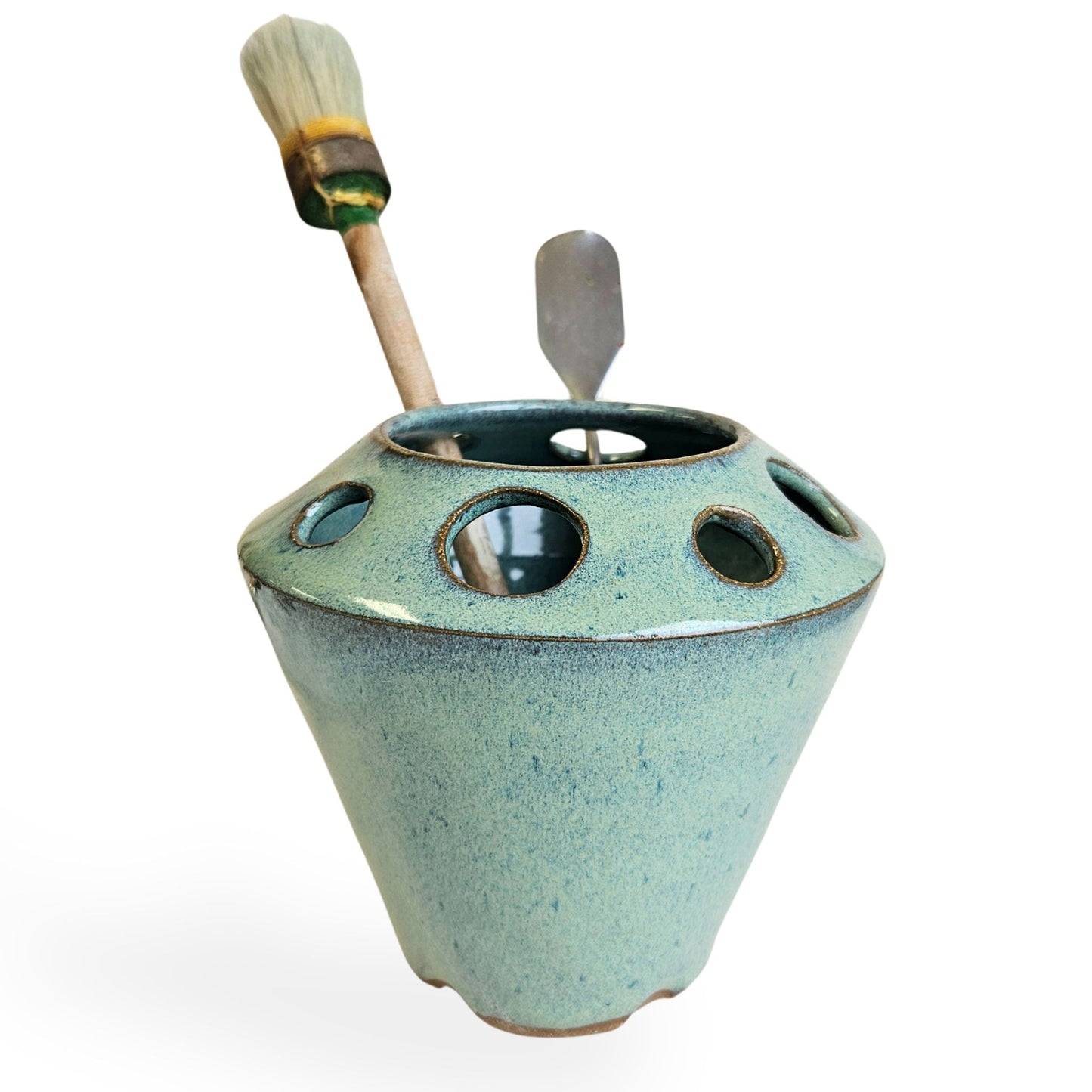 Handmade ceramic pottery tool caddy in green speckled glaze, featuring a flared cone shape with multiple round openings around the rim for organizing art supplies, pens, pencils, brushes, or scissors. Unique handcrafted desk organizer, perfect for artists, crafters, or pottery lovers.