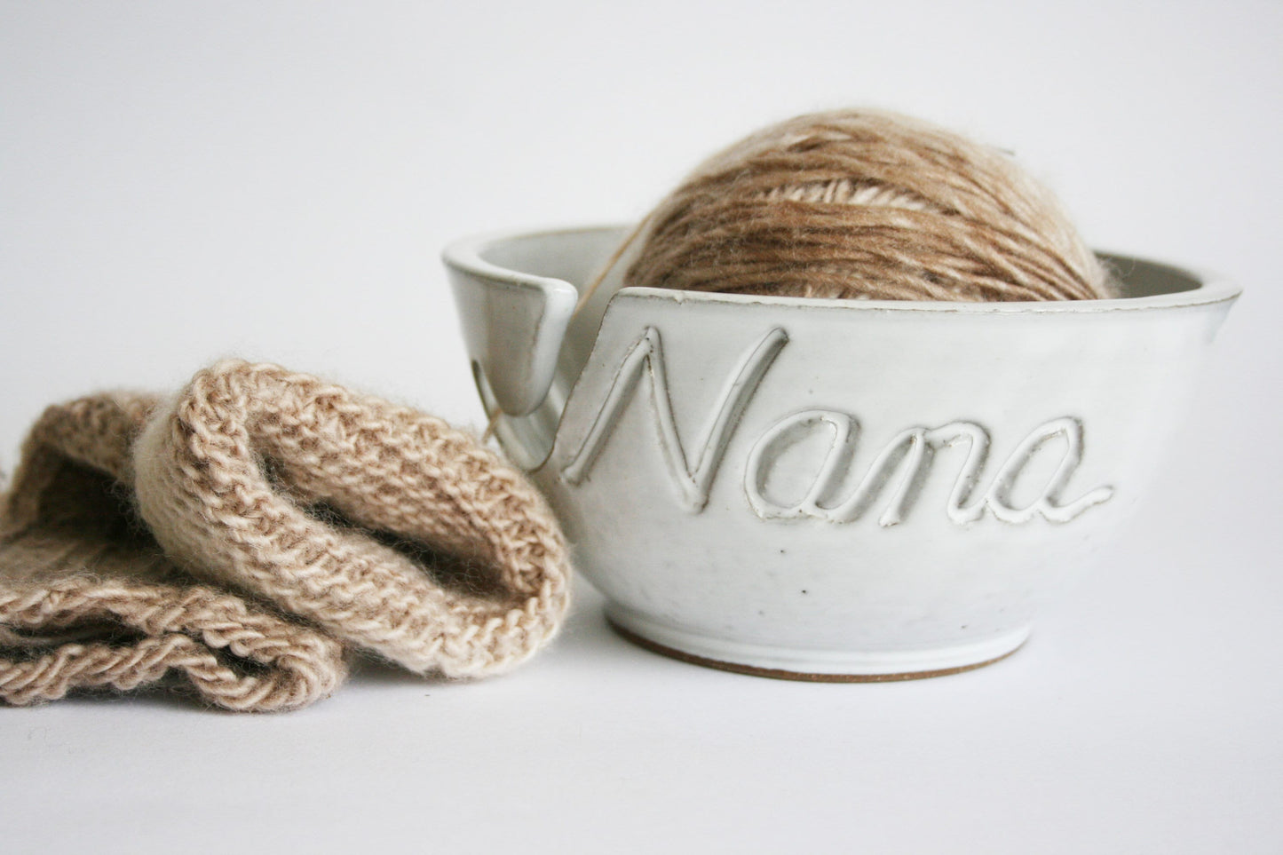 Personalized name "Nana" yarn bowl in white with a soft tan yarn ball inside it and a knitting project beside it ready for gifting