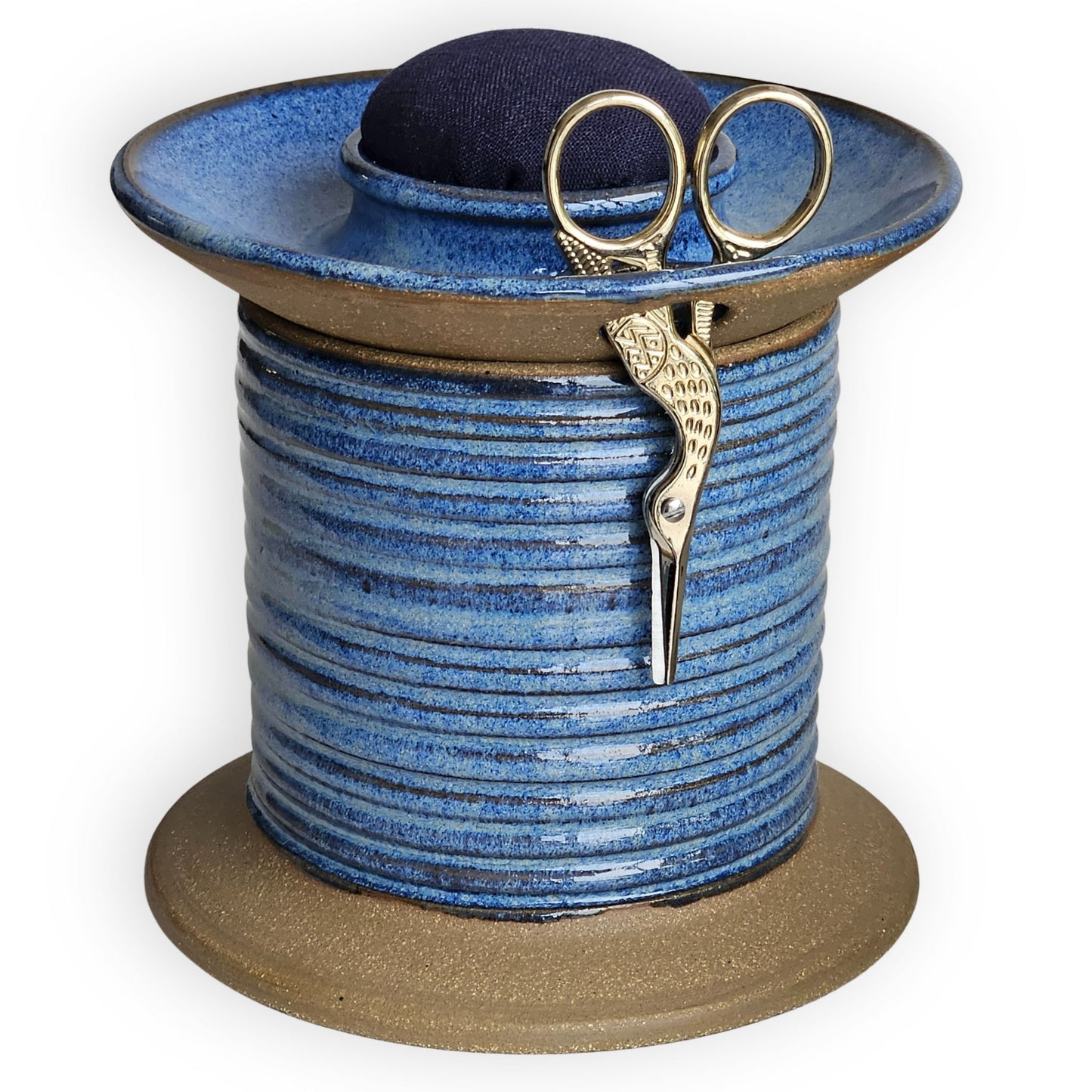 Sewing Project notions holder oversized spool-shaped caddy holding small gold scissors for runway designer.