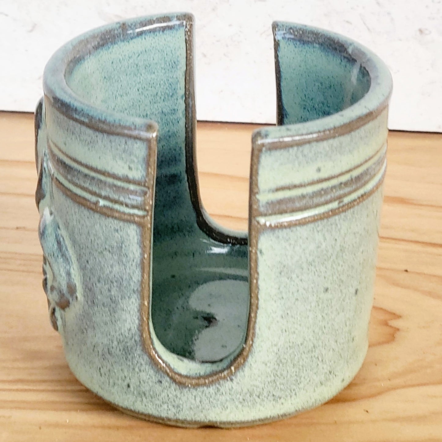 Side view of Ceramic sponge keeper with a decorative fleur-de-lis design to hold a crochet cotton yarn scrubber sponge.