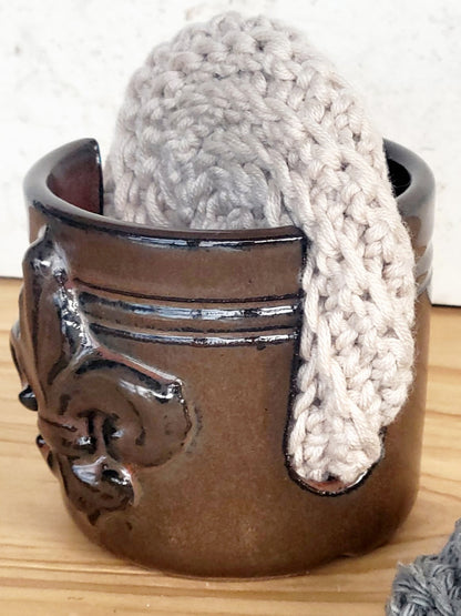 Unique handmade ceramic sponge holder with embossed fleur-de-lis, paired with a cotton crochet scrubber sponge. Functional and decorative kitchen accessory.