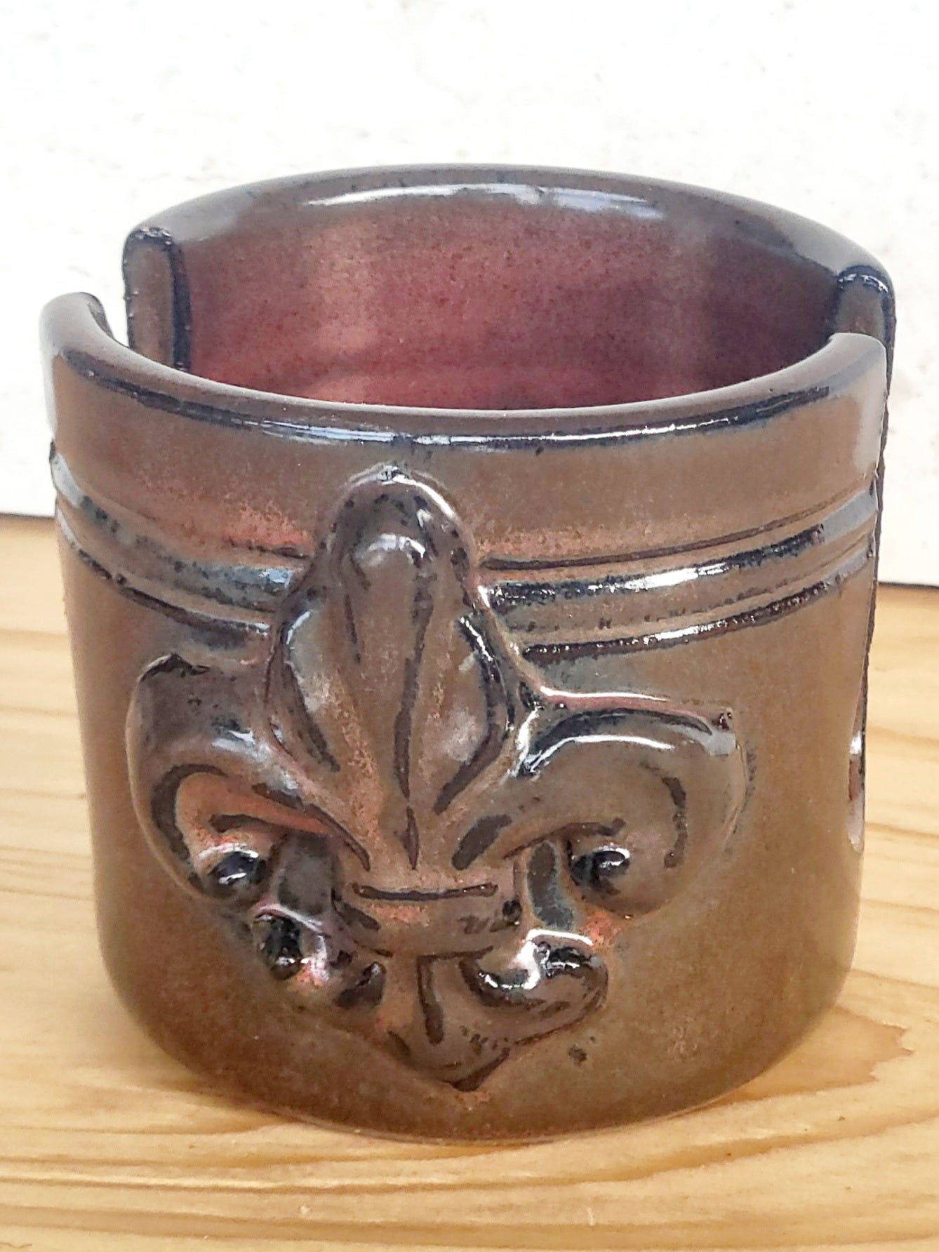 Artisan ceramic sponge keeper with fleur-de-lis accent, holding a handmade crochet dish scrubber. Ideal kitchen countertop storage. front view