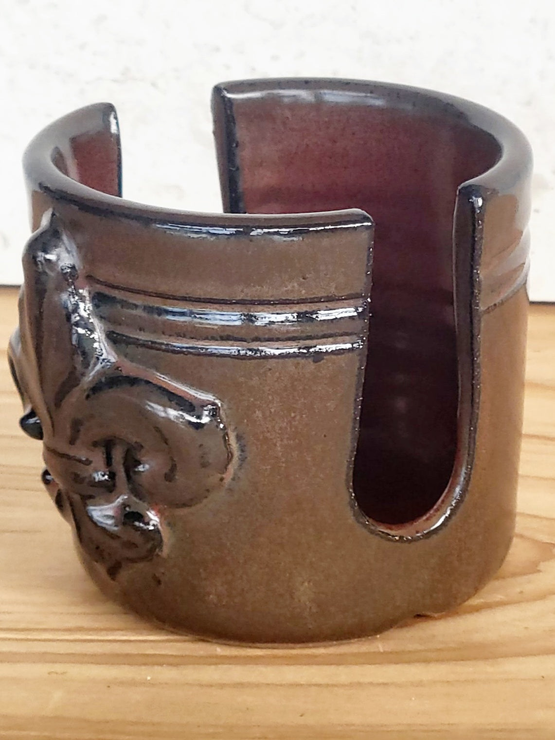 Artisan ceramic sponge keeper with fleur-de-lis accent, holding a handmade crochet dish scrubber. Ideal kitchen countertop storage. Side view