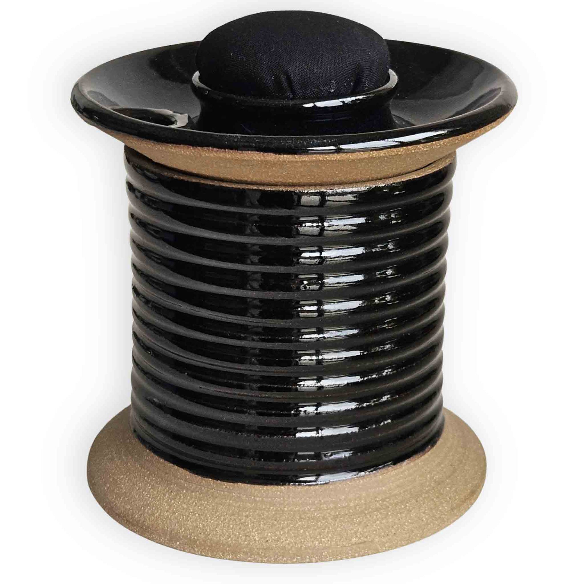 Minimalist oversized spool shaped black ceramic sewing station caddy with sleek black pincushion topper and additional storage for tape, quilting supplies and sewing notions.