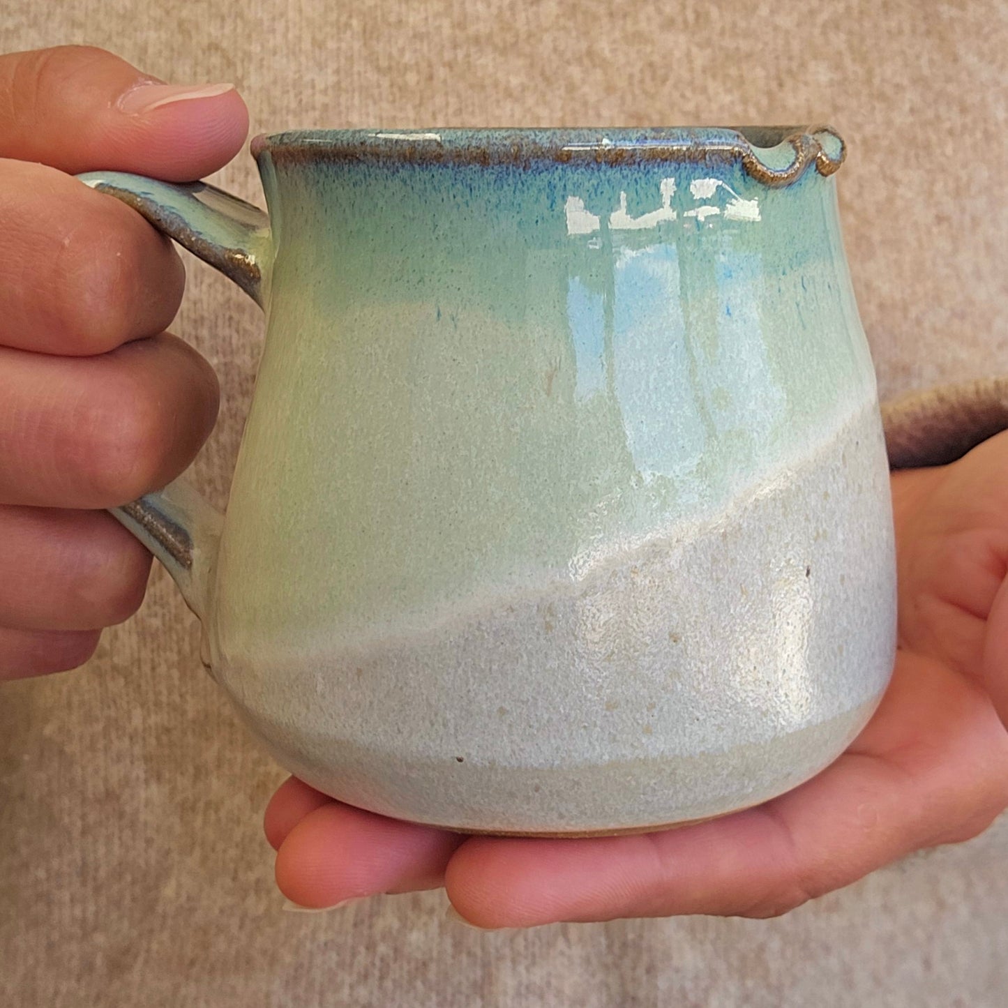 Hand holding a ceramic mug with a textured surface and gradient color.
