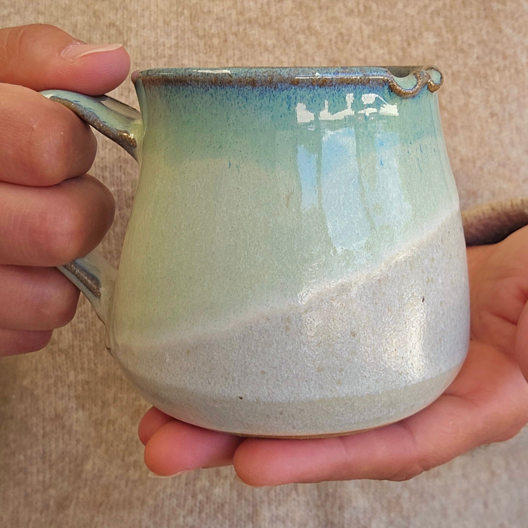 Hand holding a ceramic mug with a textured surface and gradient color.