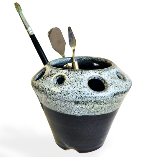 Handmade ceramic pottery tool caddy in black glaze, featuring a flared cone shape with multiple round openings around the rim for organizing art supplies, pens, pencils, brushes, or scissors. Unique handcrafted desk organizer, perfect for artists, crafters, or pottery lovers.