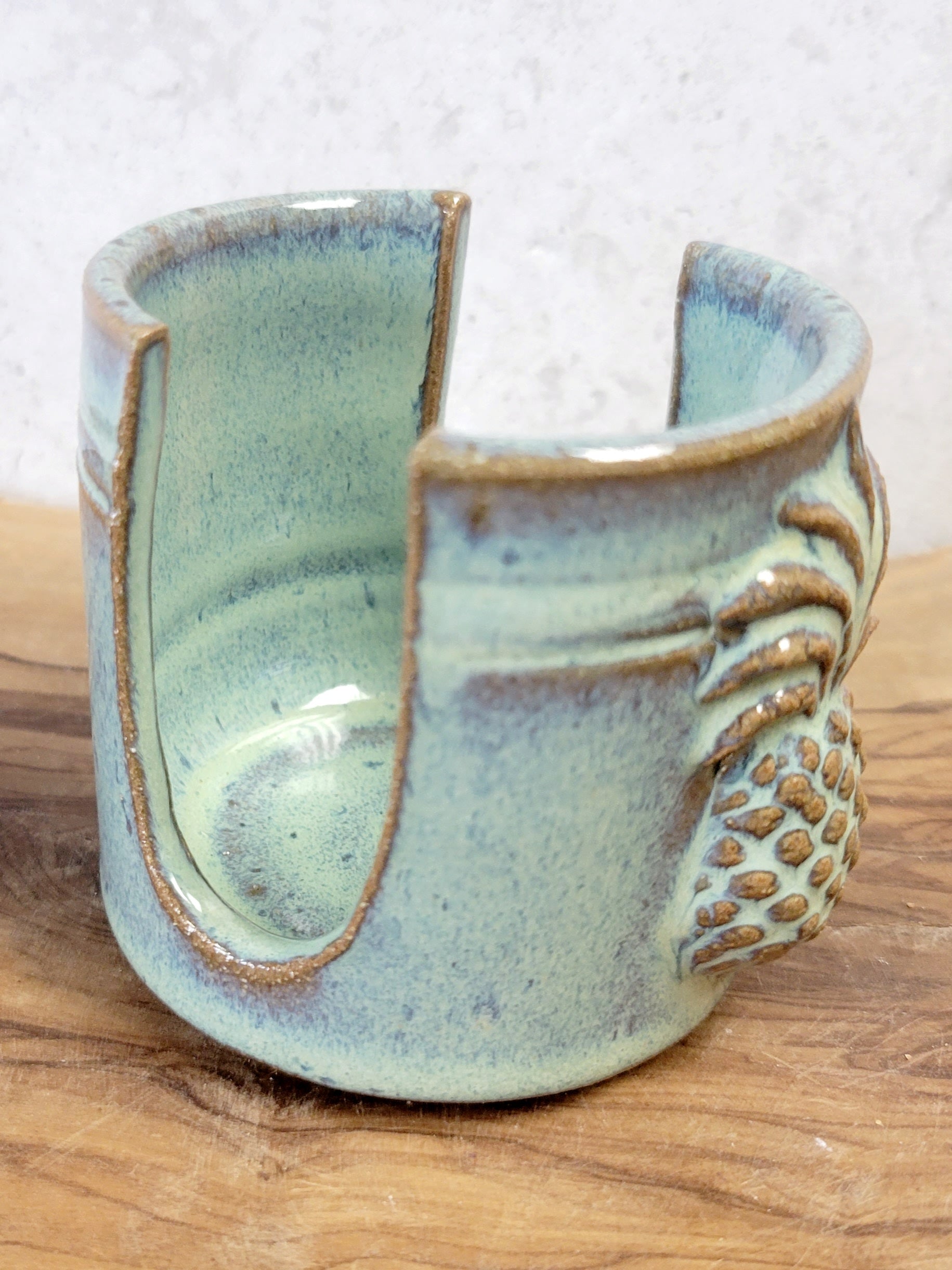 Handmade artisan green ceramic sponge holder with embossed pineapple, can hold a cotton crochet scrubber sponge. Eco-friendly kitchen countertop accessory perfect for storing crochet scrubbers, dish sponges, and sink cleaning essentials. Side view.