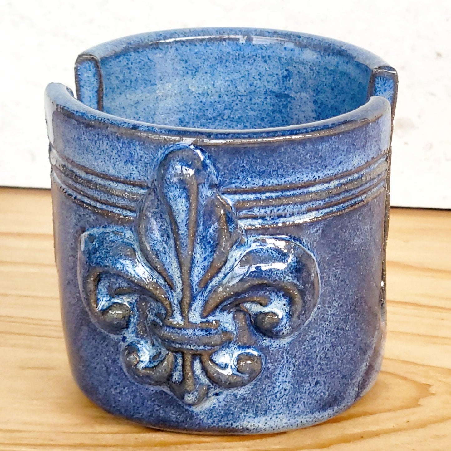 Front view of ceramic blue sponge keeper with a decorative fleur-de-lis design. This design can hold a crochet cotton yarn scrubber sponge. Perfect for kitchen counter organization. 