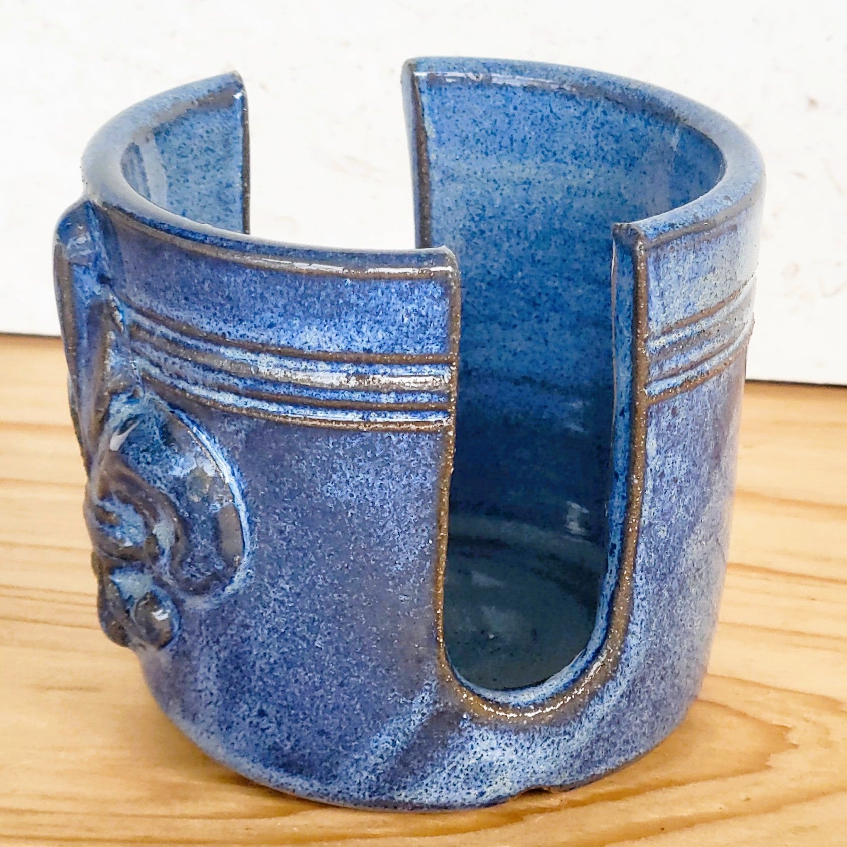 Side view of ceramic blue sponge keeper with a decorative fleur-de-lis design. This design can hold a crochet cotton yarn scrubber sponge. Perfect for kitchen counter organization. 