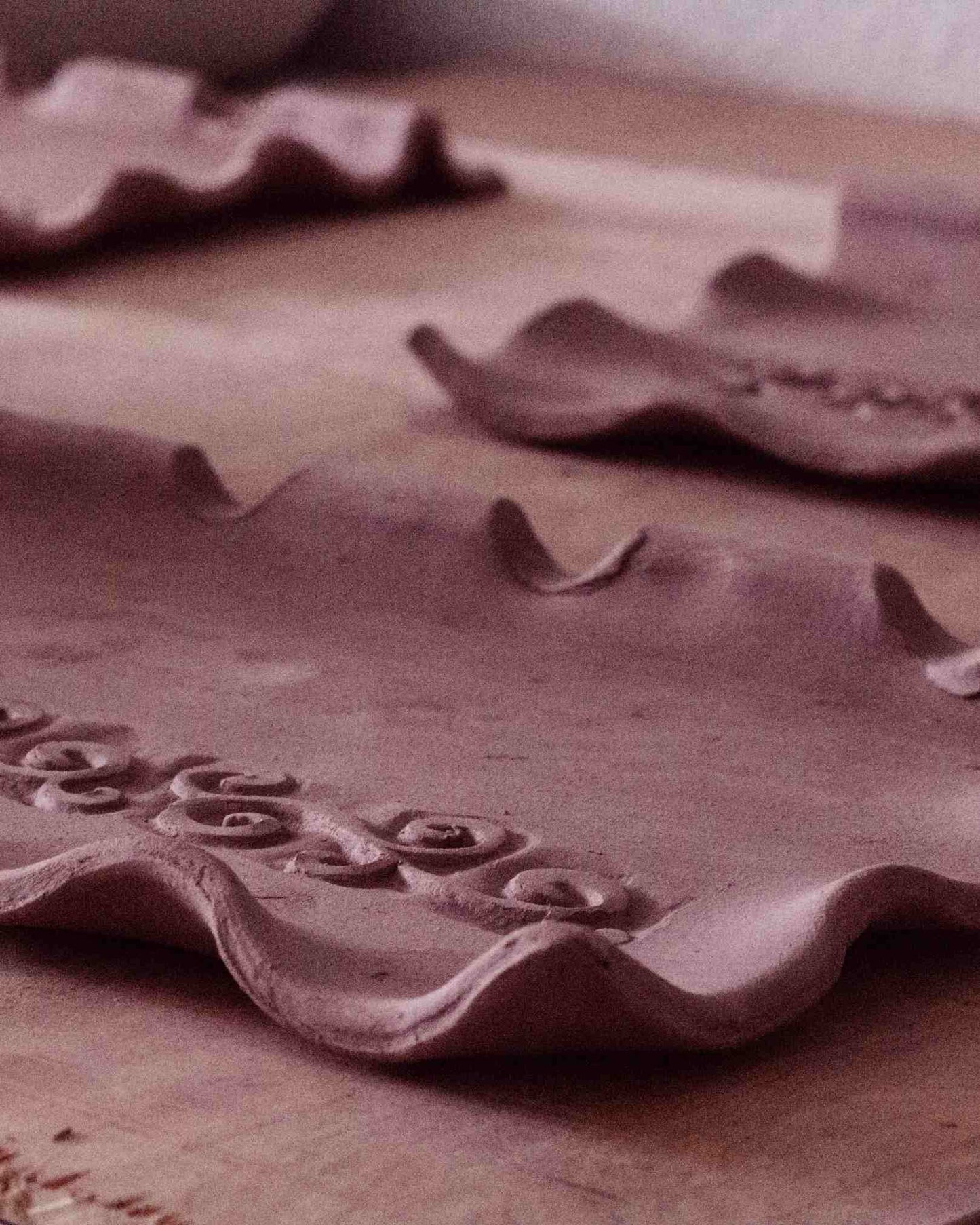 process shot of clay being formed into shapes with swirl design