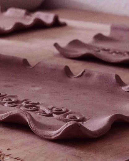 process shot of clay being formed into shapes with swirl design