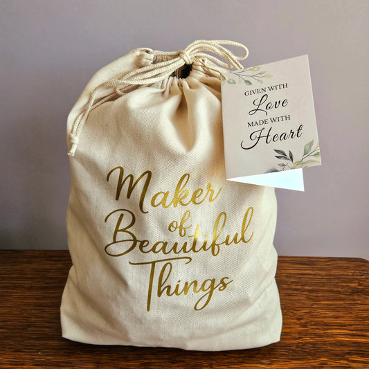 Canvas Project Gift Bag Wrap. Reusable canvas gift bag with gold “Maker of Beautiful Things” script and a gift tag that reads “Given with Love, Made with Heart.” A perfect gift wrap for handmade items, pottery, or artisan gifts — ideal for Christmas, Mother’s Day, or holiday gifting option for The Mud Place. 