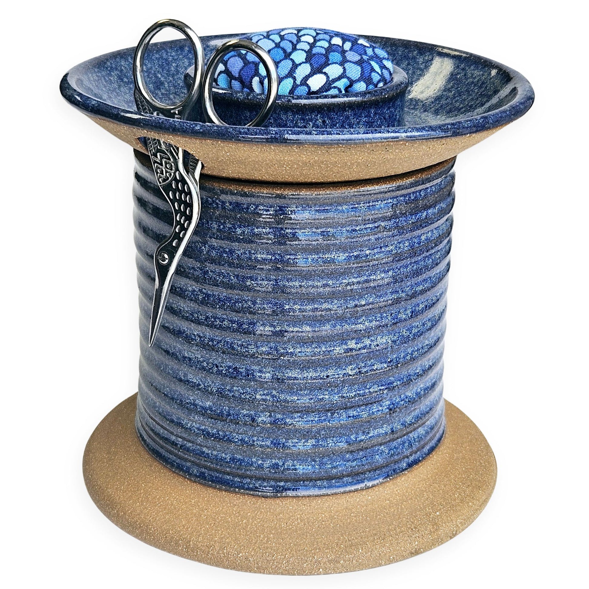 Handmade ceramic sewing caddy shaped like an oversized spool, in vibrant blue glazes, with a fabric-topped pincushion, scissors slot, and removable lid for storage. blue mermaid pincushion fabric
