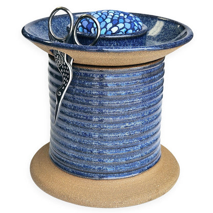 Handmade ceramic sewing caddy shaped like an oversized spool, in vibrant blue glazes, with a fabric-topped pincushion, scissors slot, and removable lid for storage. blue mermaid pincushion fabric