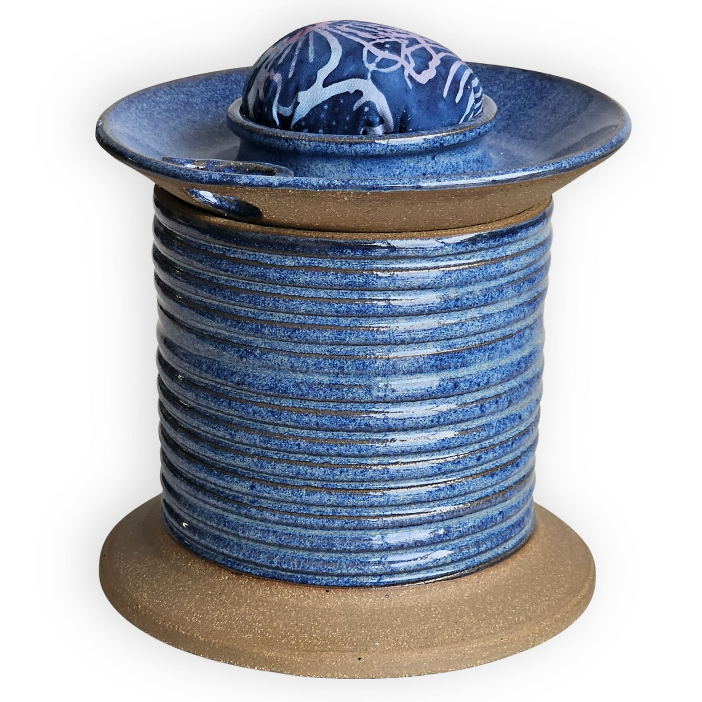 Blue ceramic sewing caddy shaped like an oversized vintage spool with batik pincushion, bobbin holder and scissor compartment with inner storage for sewing and mending supplies.