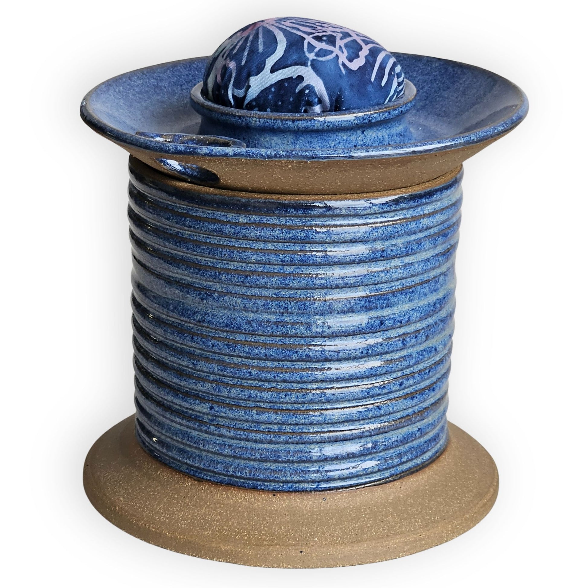 Blue ceramic sewing caddy shaped like an oversized vintage spool with batik pincushion, bobbin holder and scissor compartment with inner storage for sewing and mending supplies.
