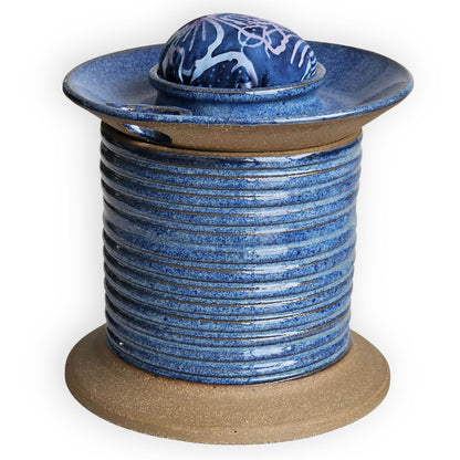 Blue ceramic sewing caddy shaped like an oversized vintage spool with batik pincushion, bobbin holder and scissor compartment with inner storage for sewing and mending supplies.