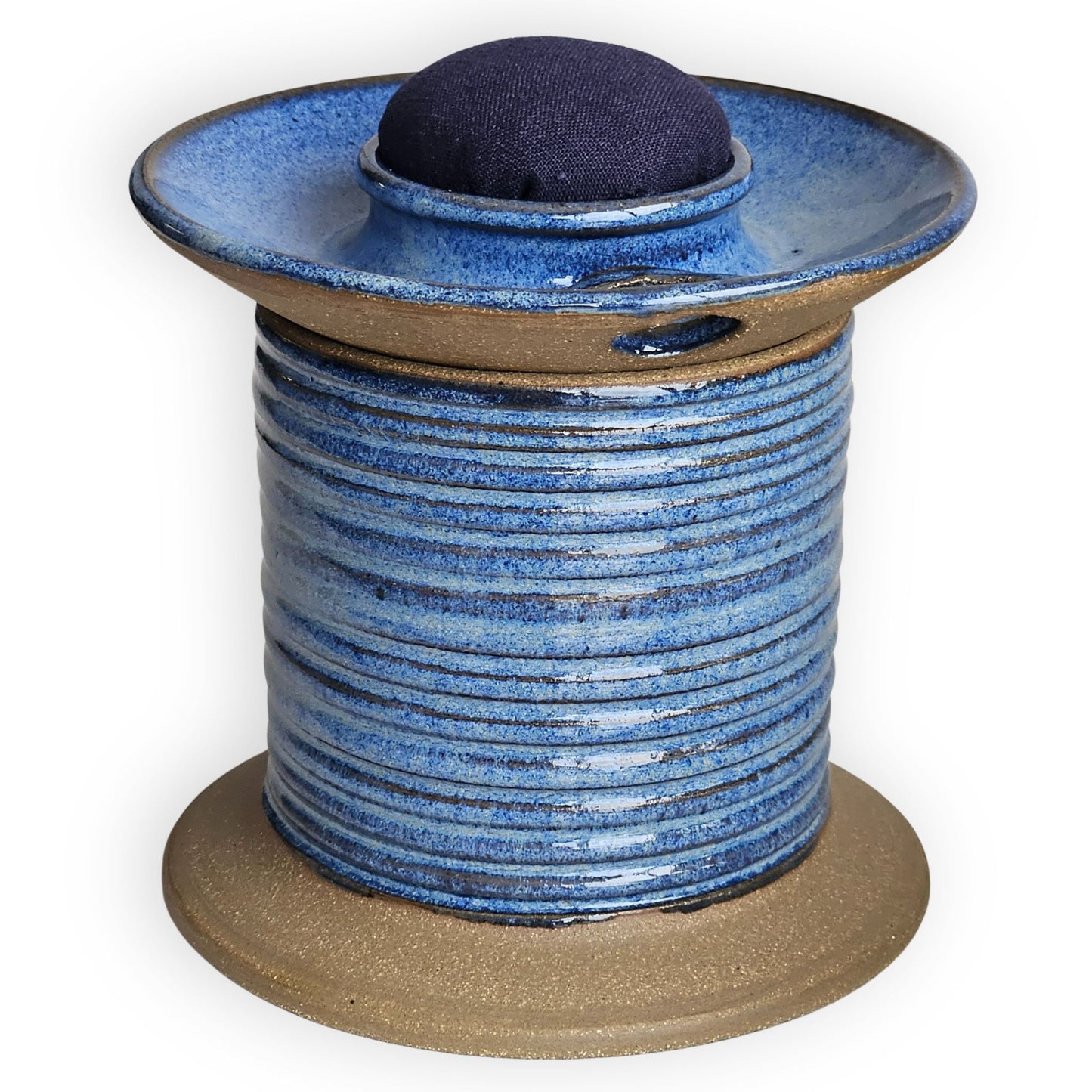 Blue ceramic sewing caddy shaped like an oversized vintage spool with navy pincushion, bobbin holder and scissor compartment with inner storage for sewing and mending supplies.