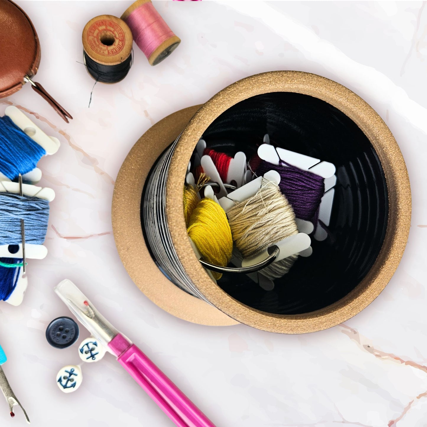 a top view of the inside of a sewing station caddy base filled with embroidery floss bobbins in many colors and seam ripper and buttons an spools of thread .