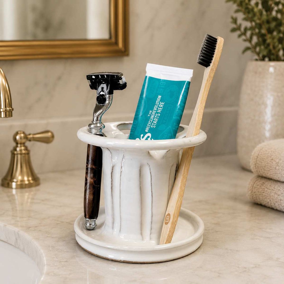 Clean organized bathroom vanity with white toothbrush and toothpaste holder plus shaving razor storage
