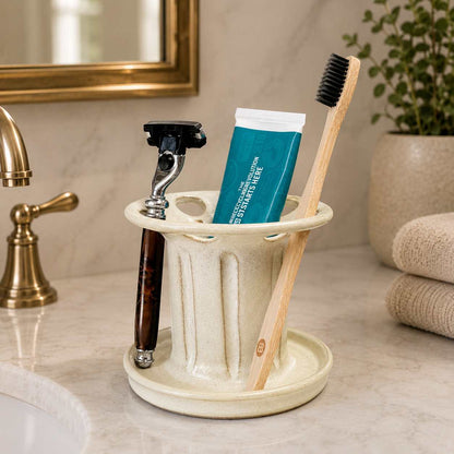 Organized bathroom vanity with cream toothbrush holder, toothpaste organizer and shaving razor storage beside the sink