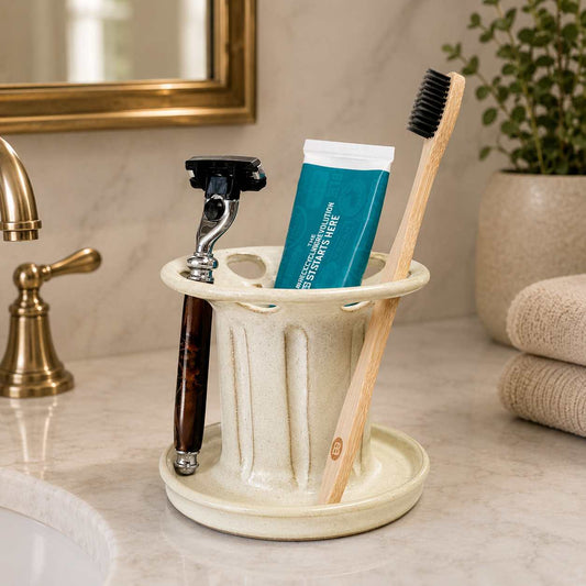 Organized bathroom vanity with cream toothbrush holder, toothpaste organizer and shaving razor storage beside the sink