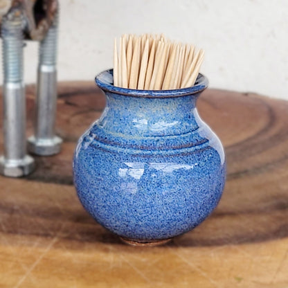 Mini blue ceramic toothpick holder on a table with hors d'oeuvres and cocktails, styled for entertaining