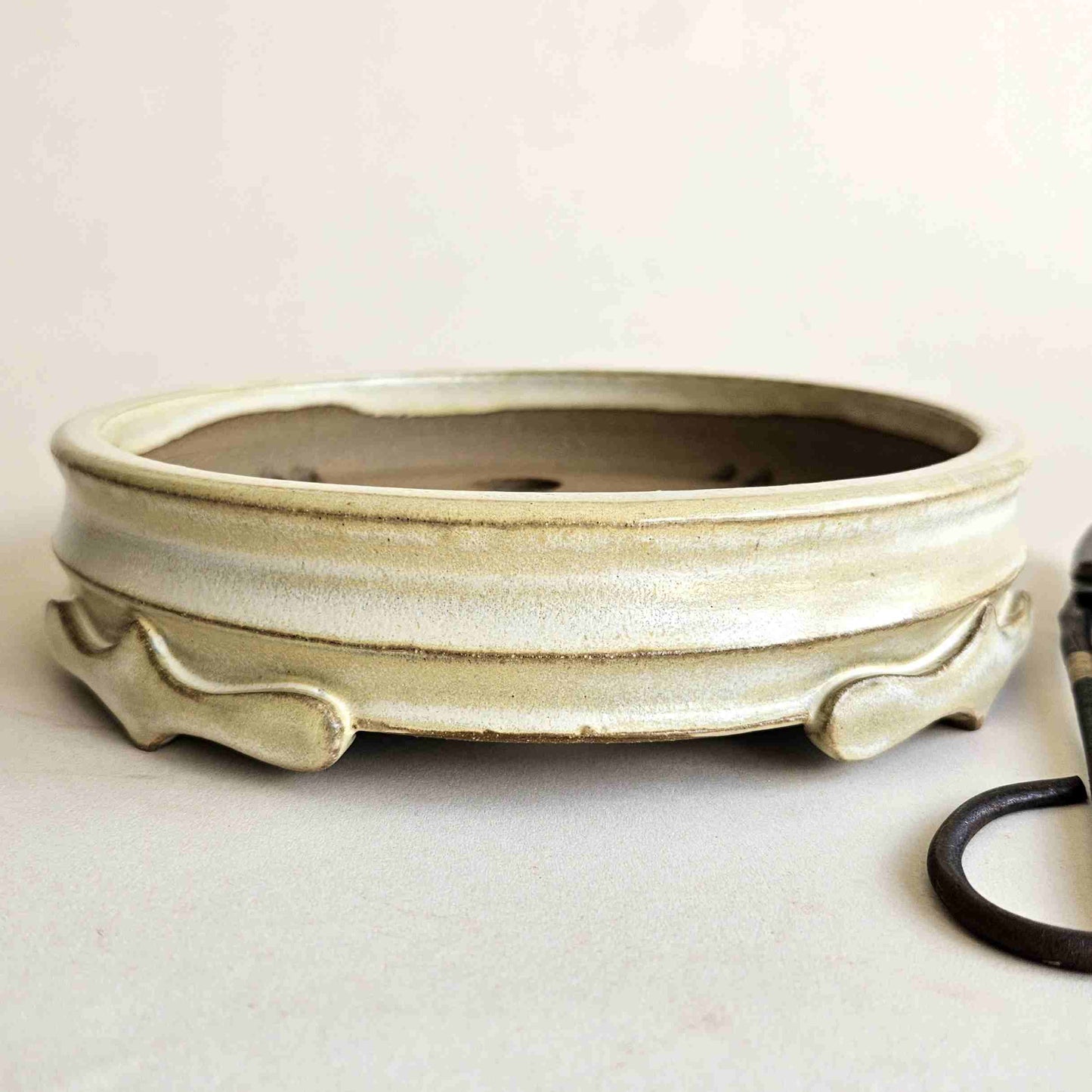 Four sculptural pointed feet with hand-shaped curved details on a yellow glazed bonsai pot.