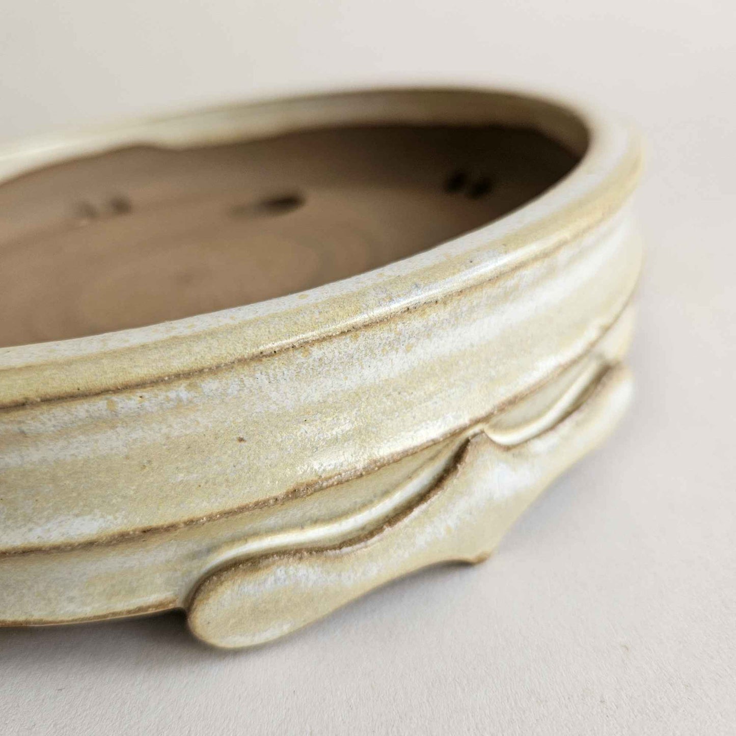 Close-up of the four pointed bonsai pot feet with dramatic hand-shaped curves and decorative details.