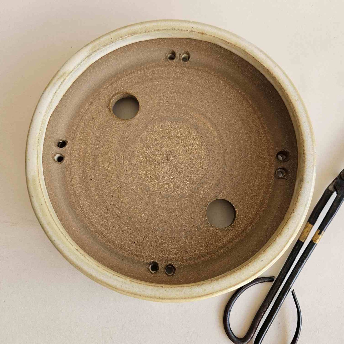 top view of bonsai pot with trimming black carbon steel sheers next to it. 