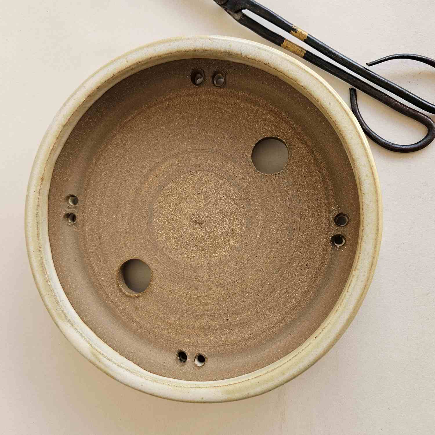 top view of bonsai pot with trimming black carbon steel sheers next to it. 