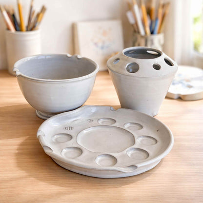 Complete handmade ceramic artist palette set including paint palette, brush holder, and rinse bowl, styled in a bright, airy studio with natural light.