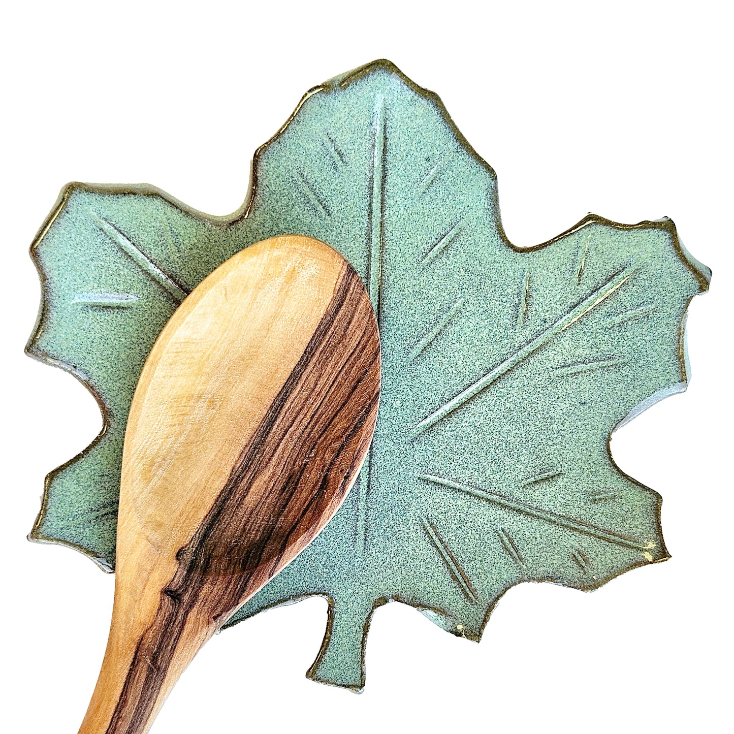 Maple leaf ceramic spoon rest in green glaze holding wooden cooking spoon