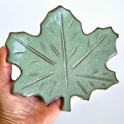 Handmade ceramic maple leaf spoon rest in hand showing glaze texture and leaf details