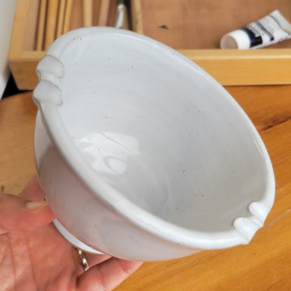 White painters ceramic brush rinse bowl held by a hand on a wooden surface